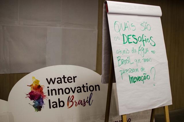 Flipchart com a pergunta "Quais são os desafios atuais da água no Brasil que mais precisam de inovação?" ao lado de um cartaz do Water Innovation Lab Brasil.