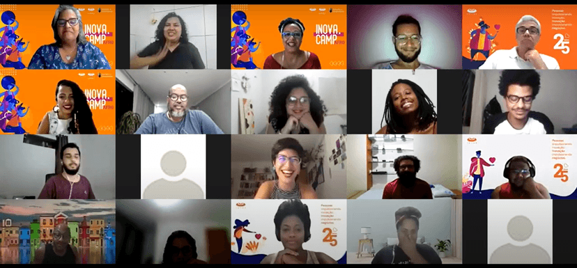 Mosaico de participantes de uma videoconferência online do Inova.Camp Afro, mostrando diversos rostos e um fundo com a logo do evento.