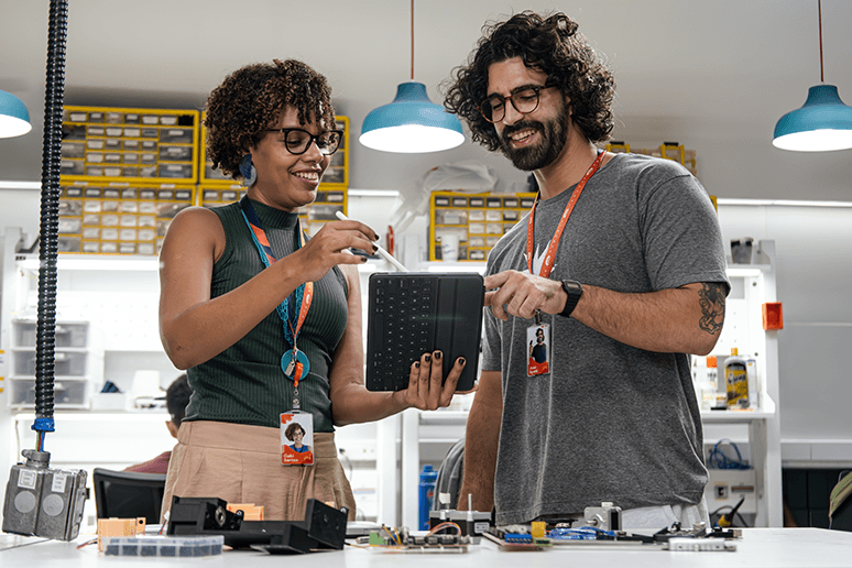 Duas pessoas em pé em uma sala olhando para um tablet