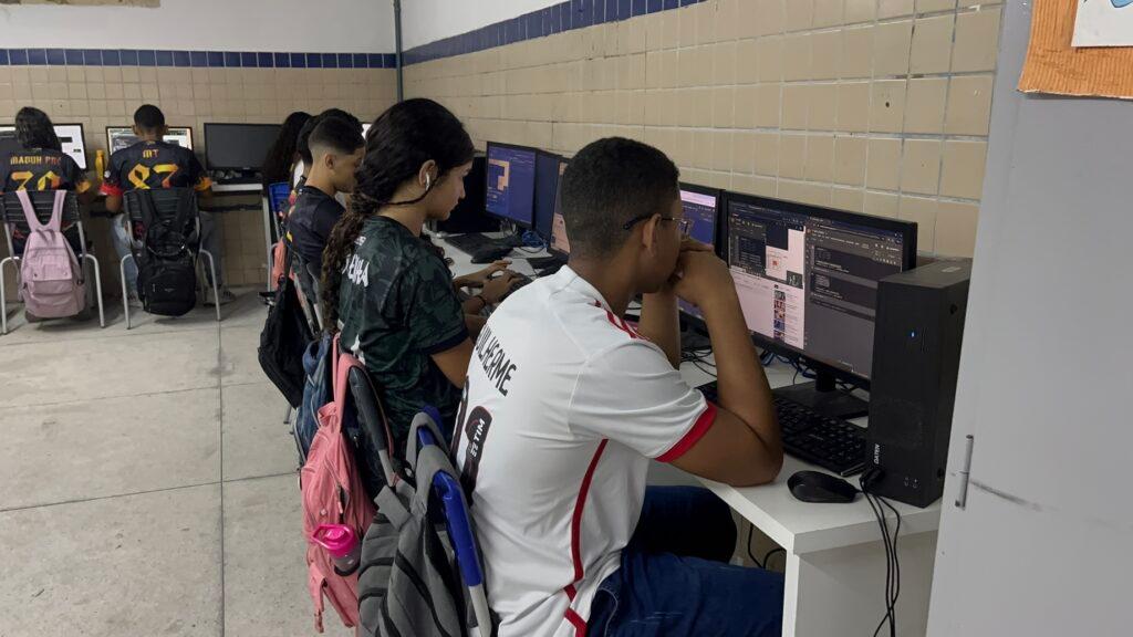 Alunos em sala de informática utilizando computadores para aulas de tecnologia.
