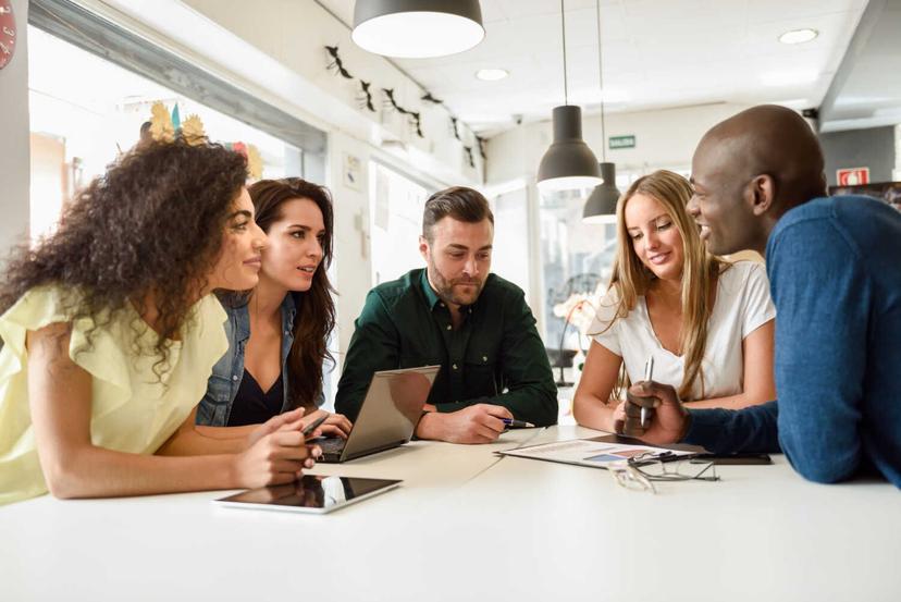 Grupo diversificado discutindo em uma mesa de trabalho.