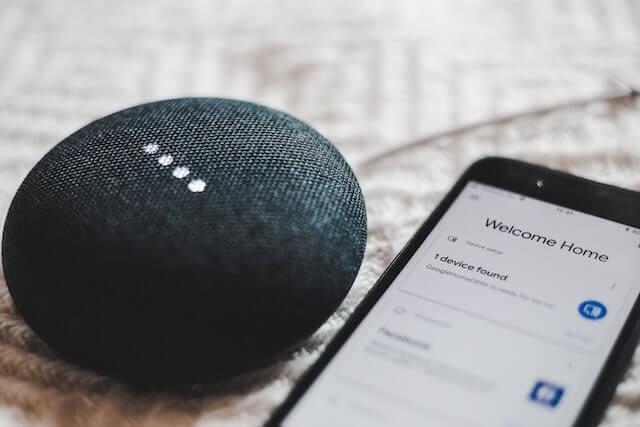Assistente virtual inteligente Google Home sendo configurado via smartphone. Internet das Coisas (IoT), casa inteligente, tecnologia doméstica.