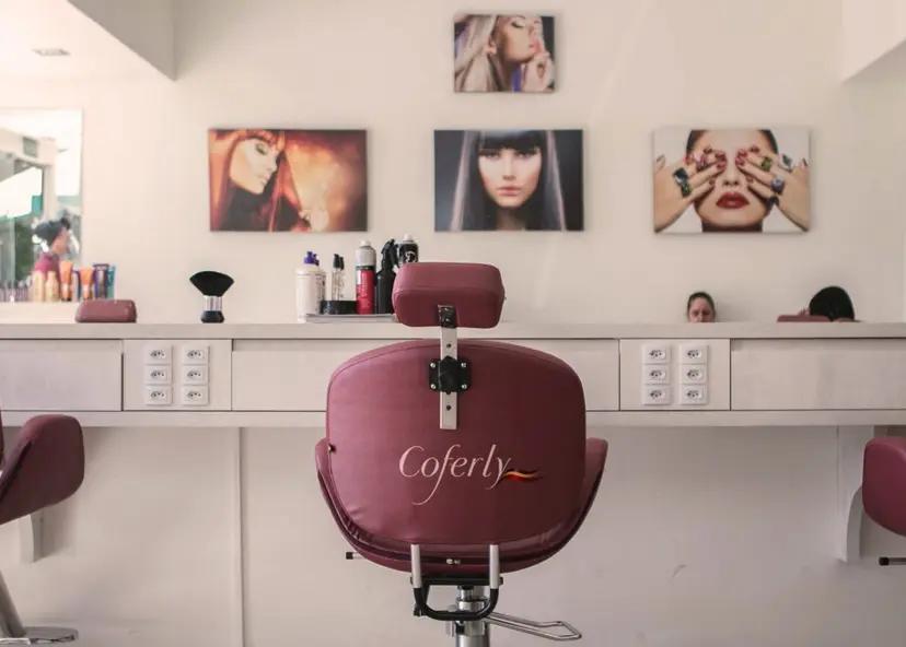 Design de serviços na Coferly potencializa o processo de inovação Cadeira de salão bordô com logo Coferly em destaque. Ao fundo, bancada branca com produtos e quadros de modelos na parede