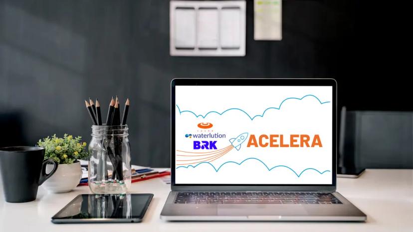 Inovação e Estratégia Empresarial no Programa Acelera da BRK e CESAR Notebook aberto em mesa de escritório exibe o logo Acelera com ícone de foguete, marcas BRK, Waterlution e CESAR ao fundo.
