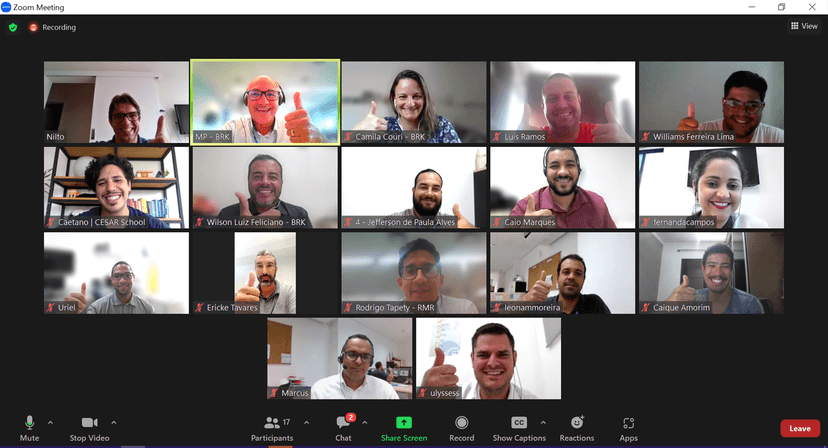 Educação corporativa para inovação em equipe remota Dezesseis pessoas em reunião online sorrindo e fazendo gesto positivo em chamada de vídeo sobre educação corporativa para inovação