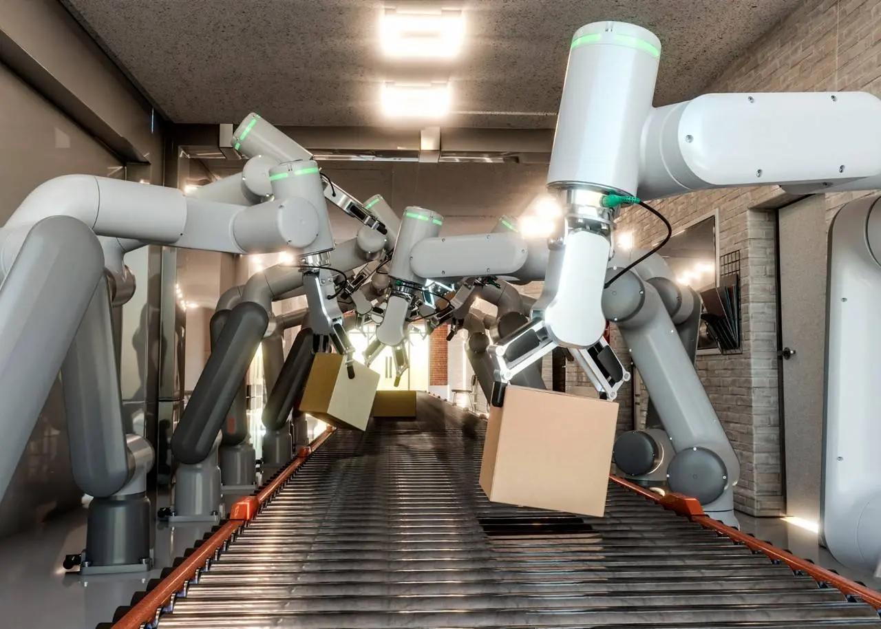 Impactos na automação e o novo perfil profissional na Indústria 4.0 Vários braços robóticos brancos organizam caixas de papelão em uma esteira rolante dentro de um centro de distribuição moderno.