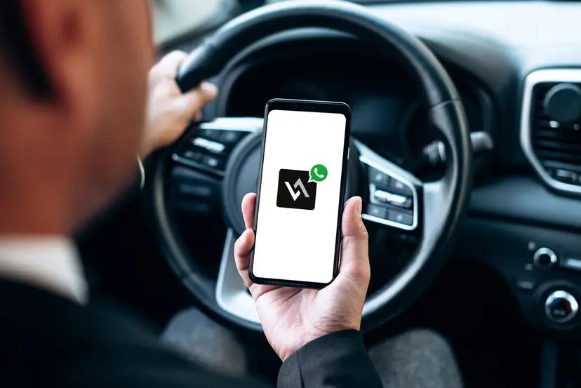 IA no setor automotivo para transformar a mobilidade Motorista segura smartphone com logo da Wings em frente ao volante de um carro. Interface digital focada em mobilidade.