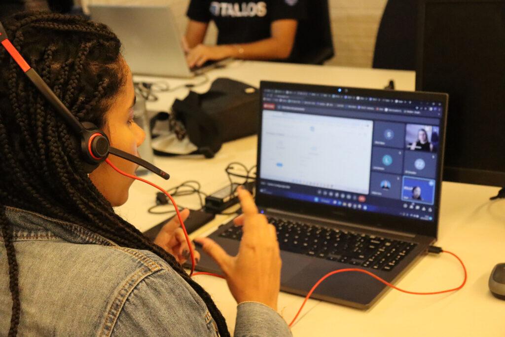 Estudante em aula online de tecnologia, usando fone de ouvido e laptop, participando de videoconferência.