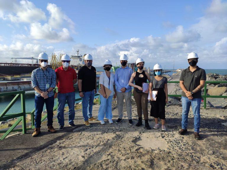 EQUIPE-DO-CESAR-EM-VISITA-AO-PORTO-DE-SUAPE-1 Equipe de engenheiros usando capacete e máscara em um porto, perto de um navio cargueiro.