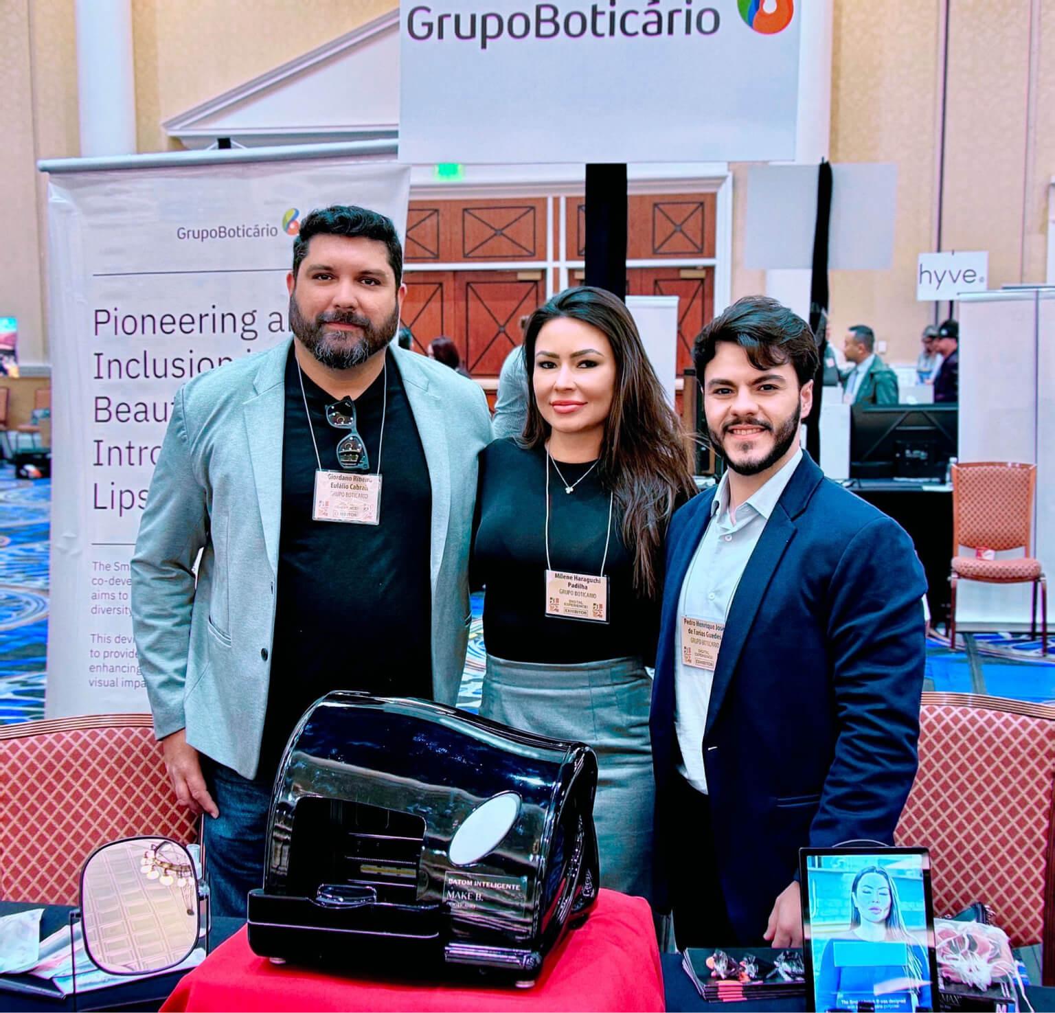 batom-inteligente-cesar-boticario-ces Dois homens e uma mulher do grupo boticário em um evento