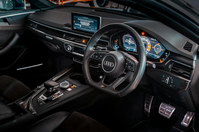 Veículos conectados e a evolução da experiência do usuário no setor Interior moderno de carro luxuoso com painel digital ligado, volante em couro e central multimídia exibindo informações de conectividade.