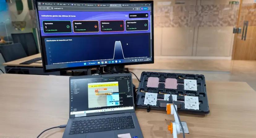 Inspeção inteligente com visão computacional Monitor exibe painel de indicadores e laptop mostra software de visão computacional analisando baterias numa bandeja preta