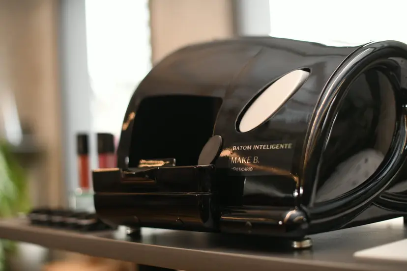 Dispositivo preto brilhante de batom inteligente Make B. sobre mesa. Equipamento de tecnologia assistiva para aplicação de maquiagem