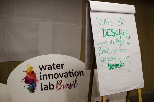 Flipchart com a pergunta "Quais são os desafios atuais da água no Brasil que mais precisam de inovação?" ao lado de um cartaz do Water Innovation Lab Brasil.