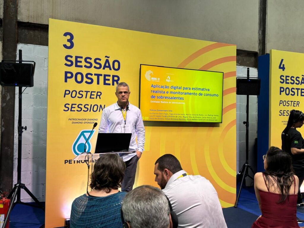 Um palestrante apresenta uma aplicação digital para estimativa e monitoramento de consumo de sobressalentes durante uma sessão de pôsteres em um evento.
