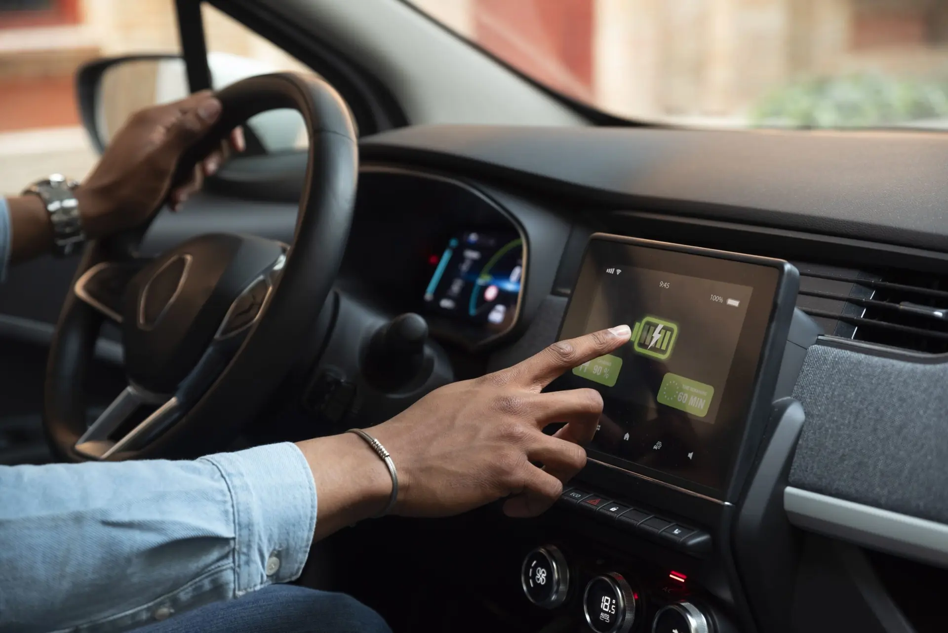 Motorista toca em tela multimídia de carro elétrico que exibe o nível de carga da bateria e tempo de carregamento.
