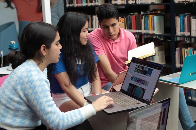jovens-estudando-biblioteca Jovens estudando juntos em biblioteca com laptops.